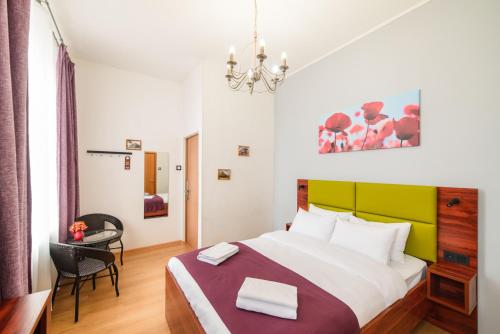 um quarto com uma cama, uma secretária e um lustre em Teplo Hotel em Vladivostok
