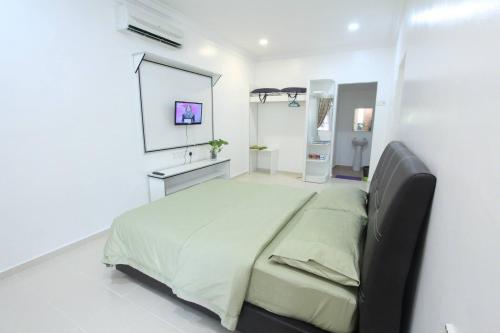 um quarto com uma cama grande num quarto branco em The Sofea Inn Transit Room Airport Kota Bharu em Pengkalan Cepa