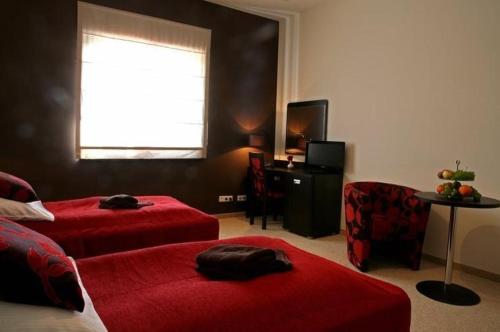 a bedroom with two beds and a chair and a window at Hotel Altamira in Piotrków Trybunalski