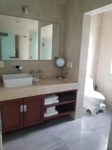 a bathroom with a sink and a toilet and a mirror at Departamento MarAzul in Cabo San Lucas