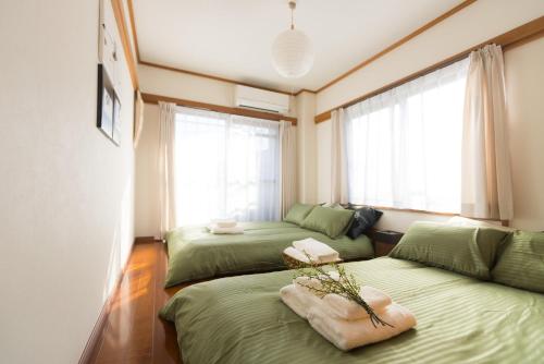 1 dormitorio con 2 camas verdes y 2 ventanas en K&K Apartment Kita-Akabane #301 en Tokio