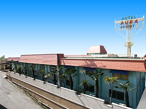 a building with palm trees next to a train station at Hotel Aura Resort Ⅰ Kashiba (Adult only) in Kashiba