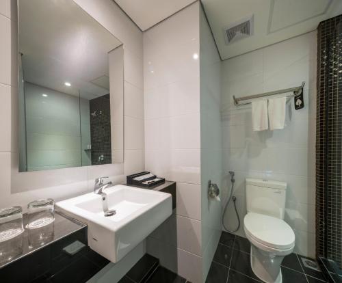 a white bathroom with a sink and a toilet at Luminor Hotel Jemursari By WH in Surabaya