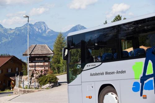 a white bus parked next to a sign with mountains at Hotel Arvenbüel in Amden