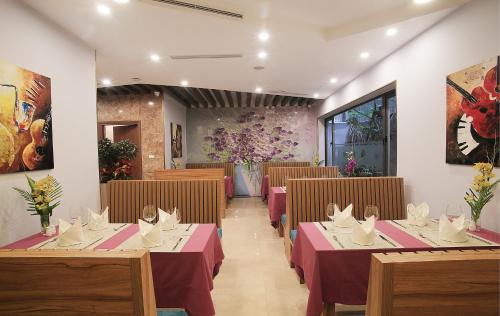 a dining room with tables and chairs and flowers at Oriana Hotel in Hanoi