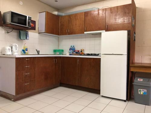 a kitchen with a white refrigerator and wooden cabinets at Access Units in Lungga