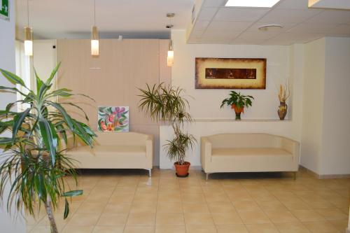 a waiting room with two white chairs and plants at La Lanterna Hotel in Rometta Marea