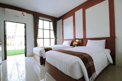 two beds in a room with two windows at Nonghan Grand Hotel and Resort in Nong Han