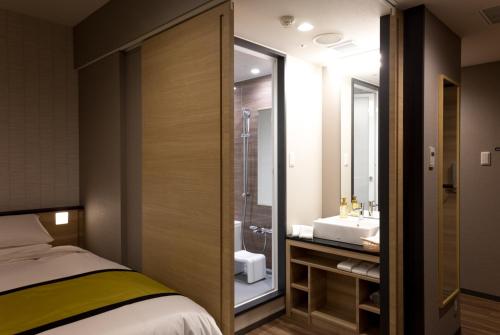 a bathroom with a bed and a sink and a shower at Hotel Hewitt Koshien in Nishinomiya