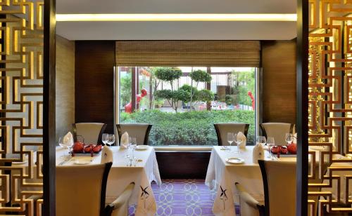 a restaurant with white tables and chairs and a window at Radisson Blu Hotel, Indore in Indore