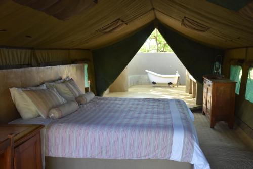 a bedroom with a tent with a bed and a tub at Koro Island Camp in Mathathane