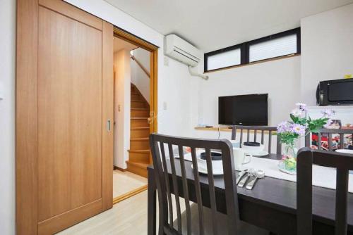 a dining room with a table and a television at Luxury Guest House in Tokyo Shinjuku in Tokyo