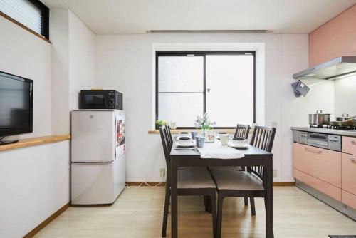 a kitchen with a table with chairs and a refrigerator at Luxury Guest House in Tokyo Shinjuku in Tokyo