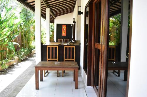 um alpendre com uma mesa de madeira e um lavatório em Meisya Cottage em Gili Trawangan