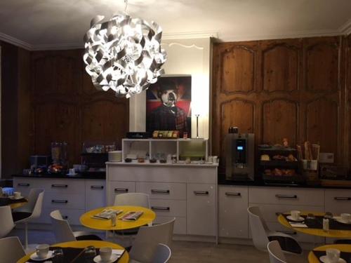 une cuisine avec des tables et des chaises et un lustre dans l'établissement Hôtel Atlantic, à La Rochelle