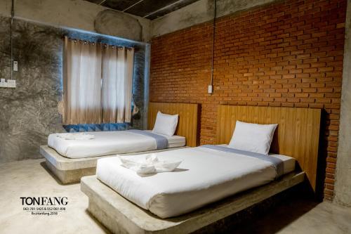 two beds in a room with a brick wall at Ton Fang Hotel in Fang