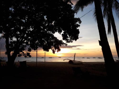 a sunset on the beach with a swing at Big BamBoo Beach Resort Sipalay in Sipalay