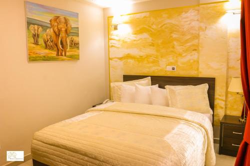 a bedroom with a bed with a painting on the wall at Noubou International Hotel in Douala