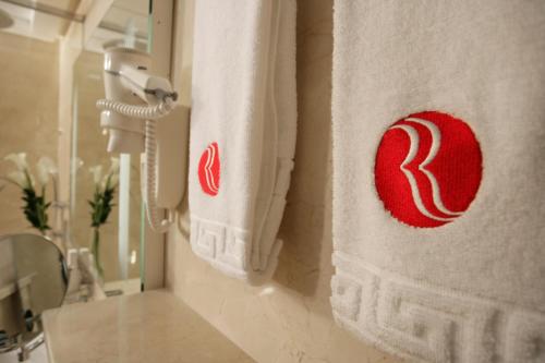 a bathroom with a towel with a red logo on it at Ramada Hotel & Suites by Wyndham Ajman in Ajman 