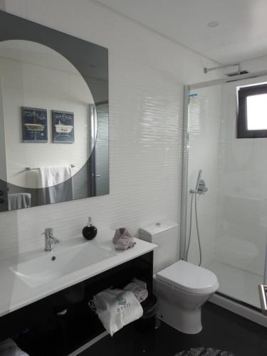 ein Badezimmer mit Waschbecken, Toilette und Spiegel in der Unterkunft RR House in Ribeira Quente