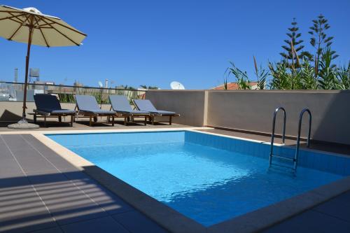 a swimming pool with chairs and an umbrella on a roof at Iolida Beach by Smile Hotels in Agia Marina Nea Kydonias