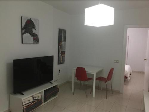sala de estar con TV y mesa con sillas en M.L Los Vicentes, en Ronda