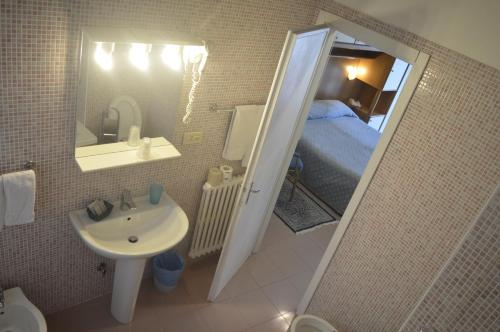 a small bathroom with a sink and a bed at Hotel Svizzera in Arma di Taggia