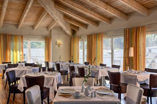 a restaurant with white tables and chairs and windows at Hotel Vier Jahreszeiten Binz in Binz