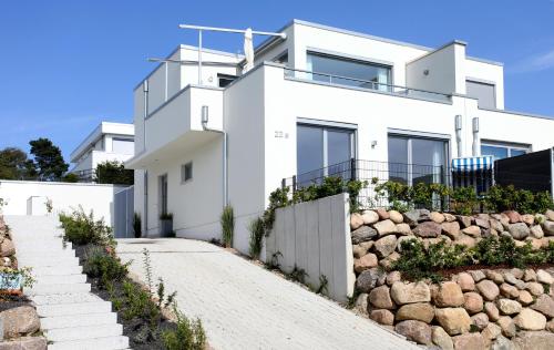 ein weißes Haus mit einer Steinwand in der Unterkunft Villa Sonneninsel in Binz - mit Sauna und zwei Terrassen in Binz