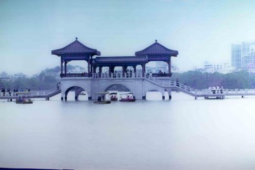 a bridge over a river with boats in the water at 7Days Inn Huizhou West Lake in Huizhou