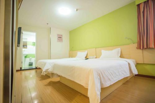 two beds in a room with green walls at 7Days Inn Huizhou West Lake in Huizhou