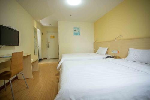 a hotel room with two beds and a desk and a tv at 7Days Inn Huizhou West Lake in Huizhou