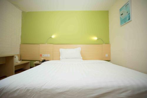 a bedroom with a large white bed with two lights at 7Days Inn Huizhou West Lake in Huizhou