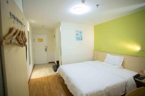 a bedroom with a white bed and a green wall at 7Days Inn Huizhou West Lake in Huizhou