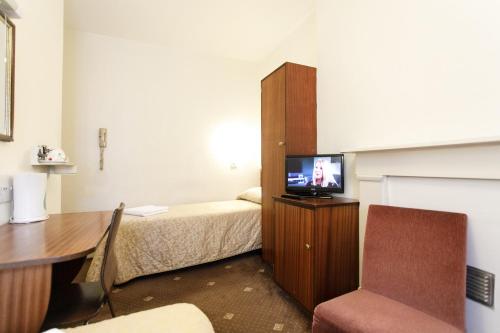 a room with a bed and a desk and a television at Jesmond Hotel in London
