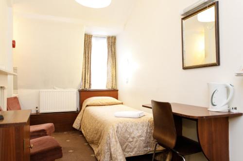 a bedroom with a bed and a desk and a table at Jesmond Hotel in London
