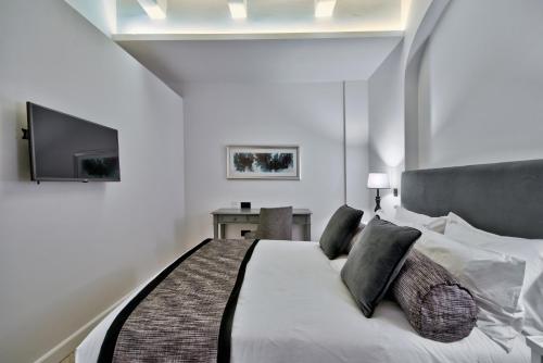 a bedroom with a large white bed and a television at 66 Saint Paul's & Spa in Valletta