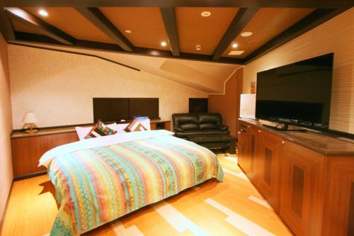 a bedroom with a bed and a flat screen tv at Sari Resort Daito (Adult only) in Daitō