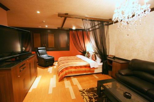 a bedroom with a bed and a couch and a television at Sari Resort Daito (Adult only) in Daitō