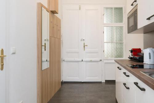 biała kuchnia z białymi szafkami i zlewem w obiekcie Vienna Stay Apartments Castellez 1020 w Wiedniu
