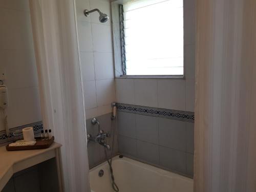 a bathroom with a shower and a tub and a window at The Meadows Resort and Spa in Aurangabad