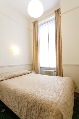 a bedroom with a bed with a large window at Jesmond Hotel in London