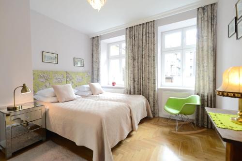 a bedroom with a bed and a green chair at Crystal Suites Chez Helena in Krakow