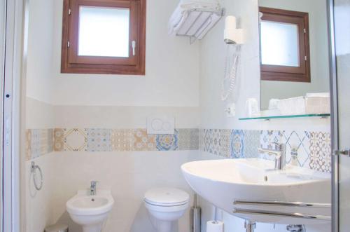 a white bathroom with a sink and a toilet at Le Macerine in Castiglione del Lago