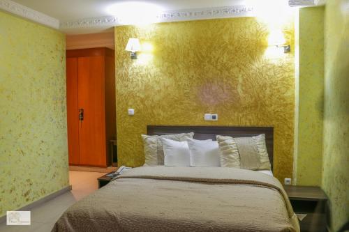 a bedroom with a bed and a yellow wall at Noubou International Hotel in Douala
