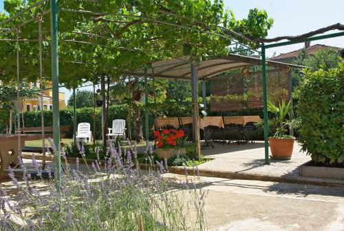 a garden with a gazebo and chairs and flowers at Apartments & Rooms BARBARA in Umag