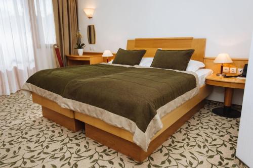 a bedroom with a large bed and a desk at Terme Zrece - Hotel Vital in Zreče