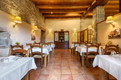 a dining room with white tables and wooden ceilings at Hotel Akerreta in Akerreta