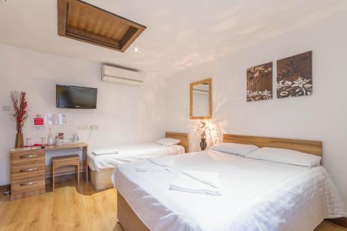 a bedroom with two beds and a desk and a tv at Brick Lane Hotel in London