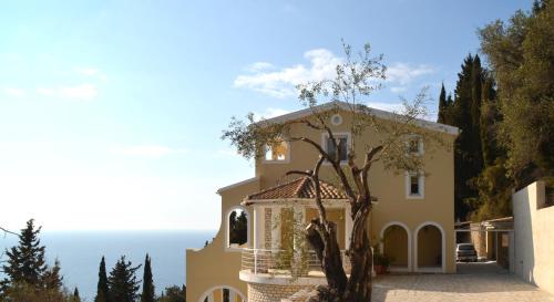 a house with a tree in front of it at Villa Alibertini in Agios Gordios